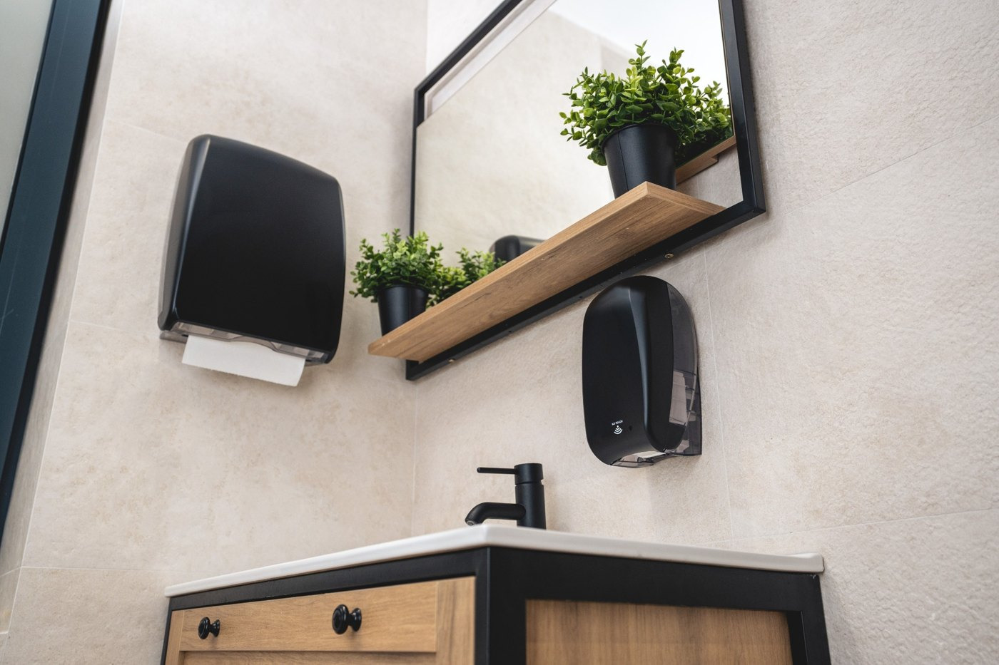 Crni dispenzeri za sapun i papirne ubruse uz lavabo u poslovnom toaletu